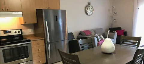 Kitchen with wooden cabinets, a refrigerator and a small dining table