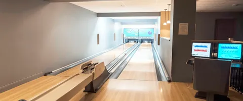 Indoor bowling lanes with scoring monitors and a seating area