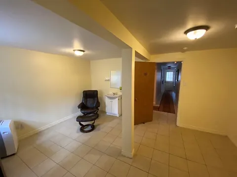 Tiled room with a black reclining chair, a sink and an open doorway