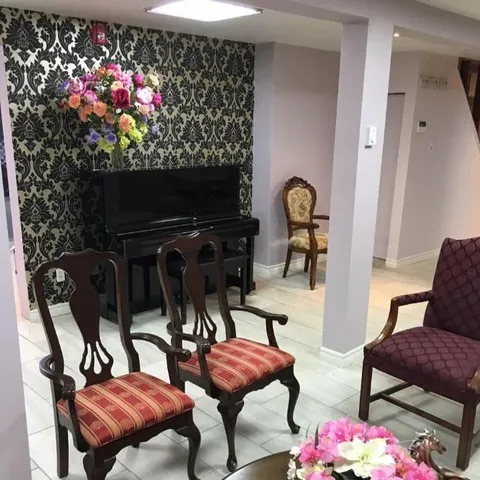Sitting area with wooden chairs, a black piano and patterned wallpaper
