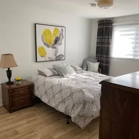 Bedroom with a bed, wooden bedside table and yellow floral wall art