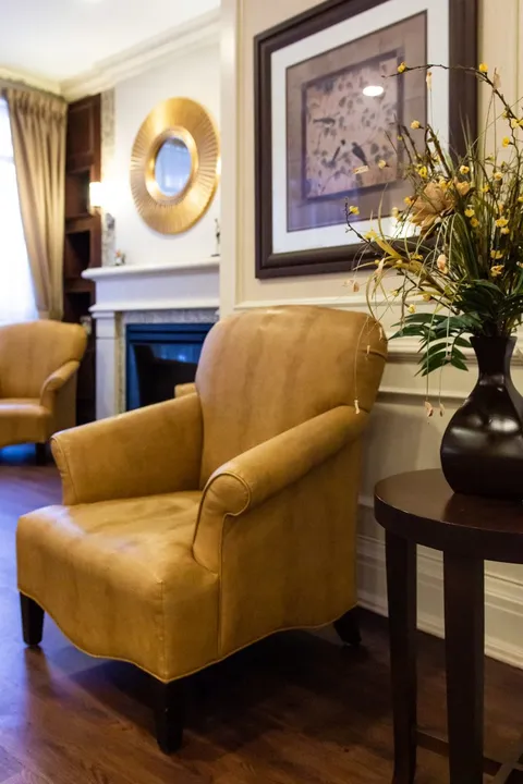 Armchairs beside a stone fireplace and framed wall art