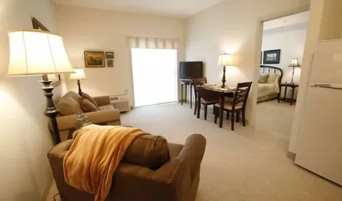 Sitting room with armchairs, dining table, lamps and a television