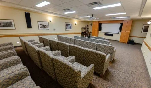 Rows of upholstered chairs facing a projection screen