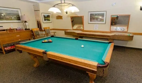 Billiards room with a pool table, pendant lights and framed wall art