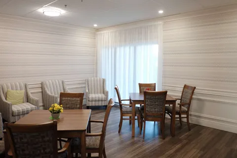 Common room with tables, chairs and striped armchairs.