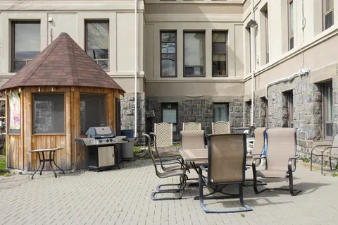 Paved patio with tables, chairs, a barbecue and a wooden shelter