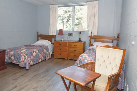 Bedroom with two single beds, a wooden dresser and an armchair