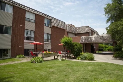 Residence exterior with brick walls, shingled roofs and a lawn