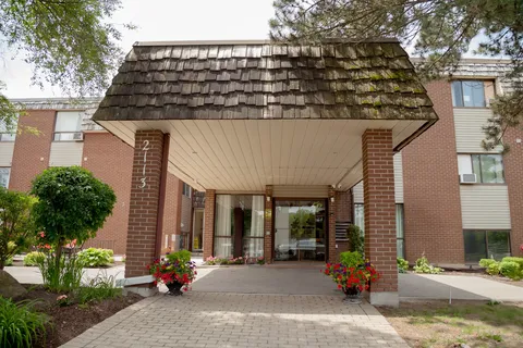 Covered entrance with brick pillars, glass doors and flower pots