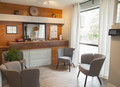Seating area with grey chairs, a mirror and a wooden cabinet