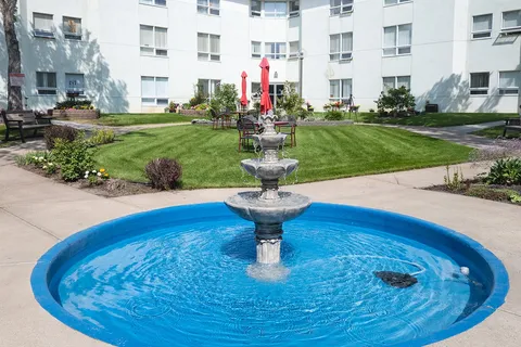 Courtyard with a fountain, shrubs and flower beds between apartment buildings