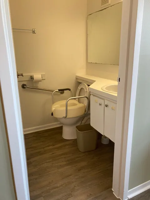 Bathroom with a sink, toilet, mirror and support rails