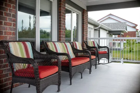 Wicker chairs with striped cushions on a covered porch.