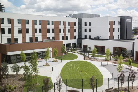 Residence buildings overlooking a courtyard with lawns and paved paths.