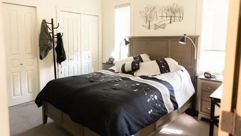 Bedroom with a black-and-white bed, bedside table and hanging coats