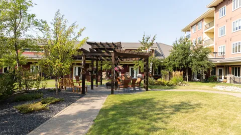 Garden courtyard with a wooden pergola, chairs, trees and lawns