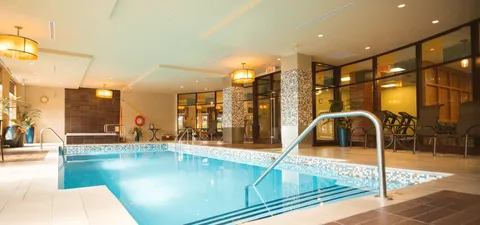Indoor swimming pool beside chairs and large windows