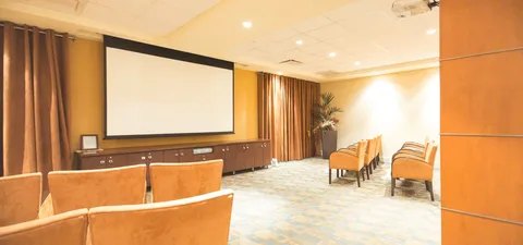 Room with rows of brown armchairs facing a blank projection screen