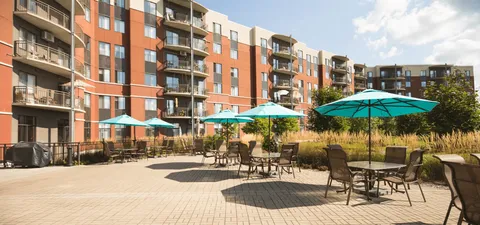 Residence with balconies beside a patio, tables and planters