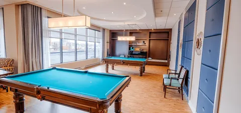 Billiards table in a room with dark chairs and a shelving unit