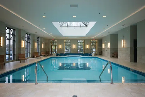 Indoor pool beneath a skylight with benches along the walls