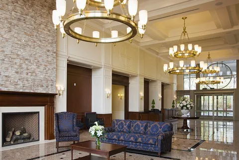Lobby with patterned seating, a stone fireplace and chandeliers