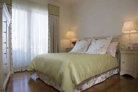 Bedroom with a pale bedspread, bedside lamps and a large window