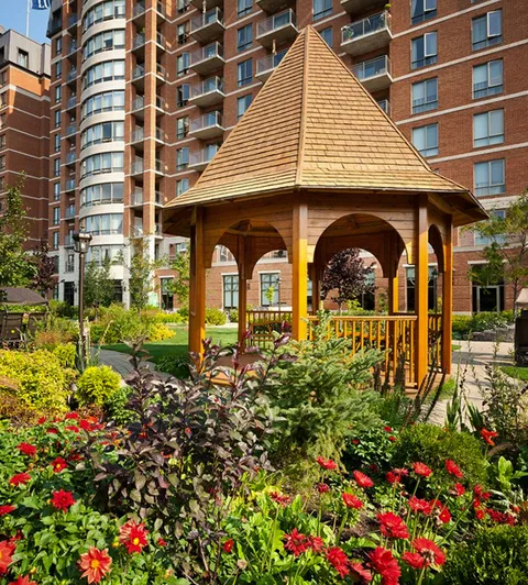 Wooden gazebo surrounded by flowers beside the residence