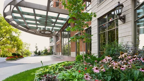 Covered entrance beside trees and flower beds