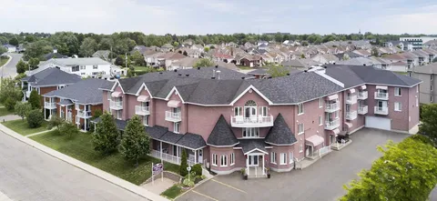 Aerial view of a brick residence with balconies, lawns and surrounding houses