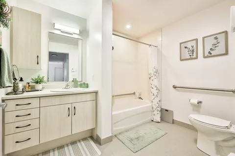 Apartment bathroom with vanity, toilet and bathtub.