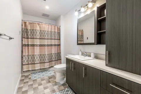 Bathroom with a vanity, mirror, shower curtain and toilet