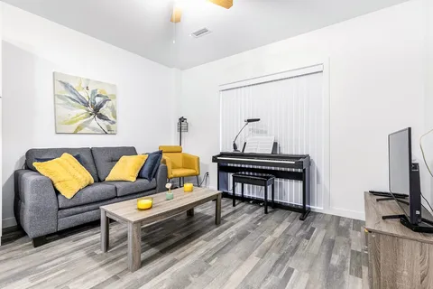 Sitting area with a grey sofa, yellow armchair, coffee table and electric piano