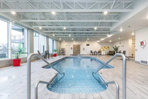 Indoor swimming pool with steps, handrails, large windows and poolside chairs