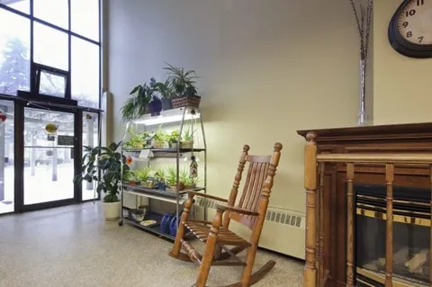 Entrance lobby with glass doors, a rocking chair, plants and a fireplace