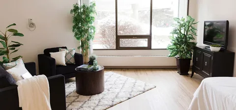 Room with armchairs, a side table, television and large windows
