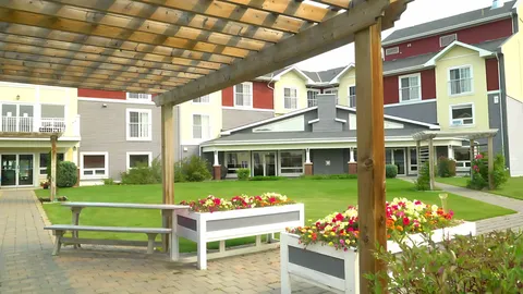 Picnic table and flower planters beneath a wooden pergola beside a lawn