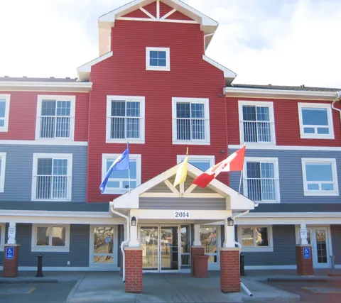Red and grey residence with a covered entrance and three flags
