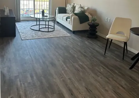 Sofa and glass coffee table beside a balcony door and dining chairs