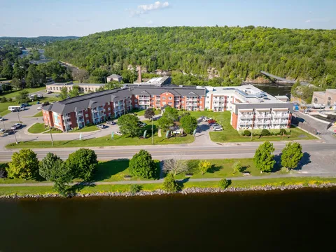 Aerial view of a red-brick residence, lawns, parking areas and a river