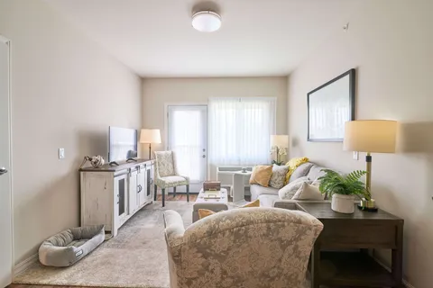 Room with a sofa, armchair, television cabinet and a door beside a window