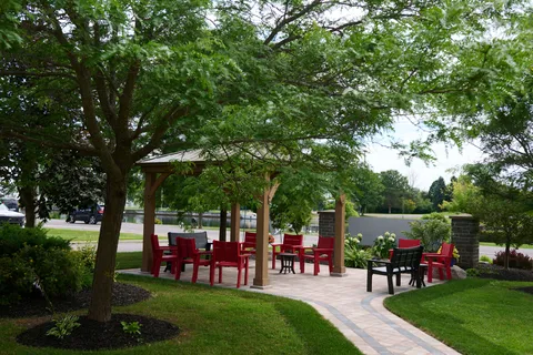 Garden seating beneath a wooden gazebo with red chairs and a curved paved path