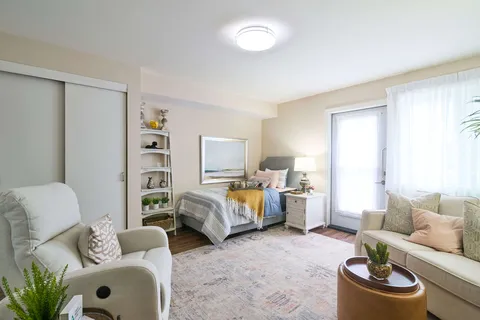 Room with a bed, armchair, sofa, shelving and a glass balcony door