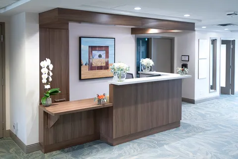 Reception counter with flowers, framed tree artwork and wood-patterned cabinetry