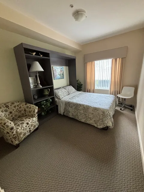 Guest suite with a bed, wardrobe and upholstered chair.