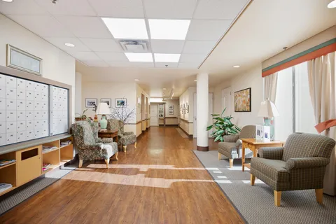 Wide corridor with seating, tables and framed wall displays.