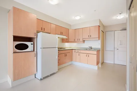 Suite kitchenette with refrigerator, microwave and wooden cabinets.