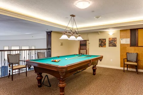 Billiards table beneath hanging lights beside a railing