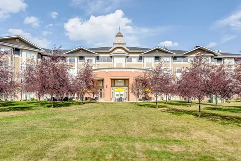 Residence building with a central entrance behind a lawn and flowering trees